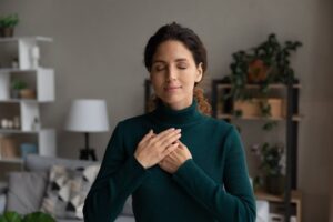 Woman with hands on heart with a soft expression, from Tess René Coaching’s article on perfection.