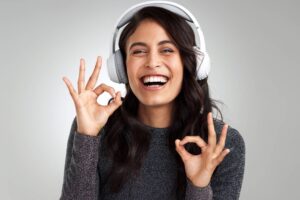Smiling woman with headphones in a Tess René Coaching article about self-worth, acceptance, and belonging.