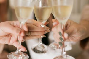 Hands raising glasses in celebration, from a Tess René Coaching article about finding small moments of joy and gratitude during challenging times.