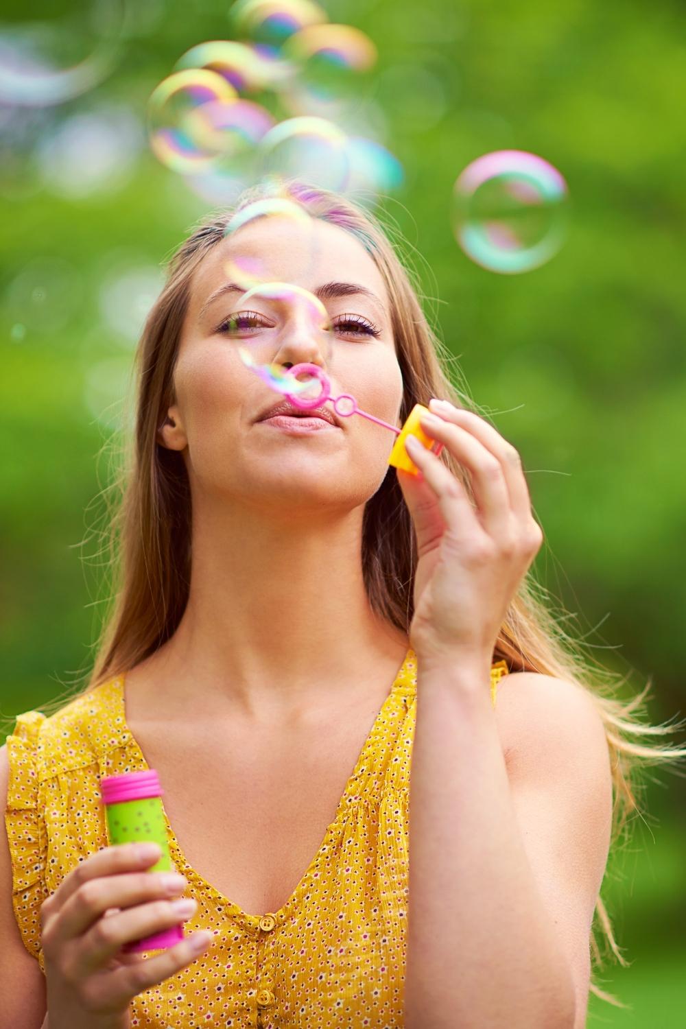woman blowing bubbles outdoors representing the playful essence of inner child healing in this Tess René Coaching article