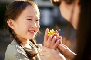 child smiling while receiving a yellow flower symbolising emotional connection and why inner child healing matters in this Tess René Coaching article