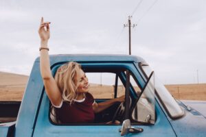 Woman smiling while driving in this Tess Rene Coaching article about building an abundance mindset through aligned choices.