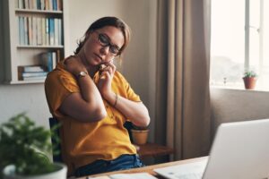 Woman rubbing her neck in this Tess Rene Coaching article about how scarcity mindset creates tension and constant pressure.