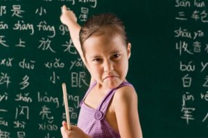 Young girl pointing at the chalkboard with intensity in this Tess Rene Coaching article about understanding the roots of hustle behaviour.