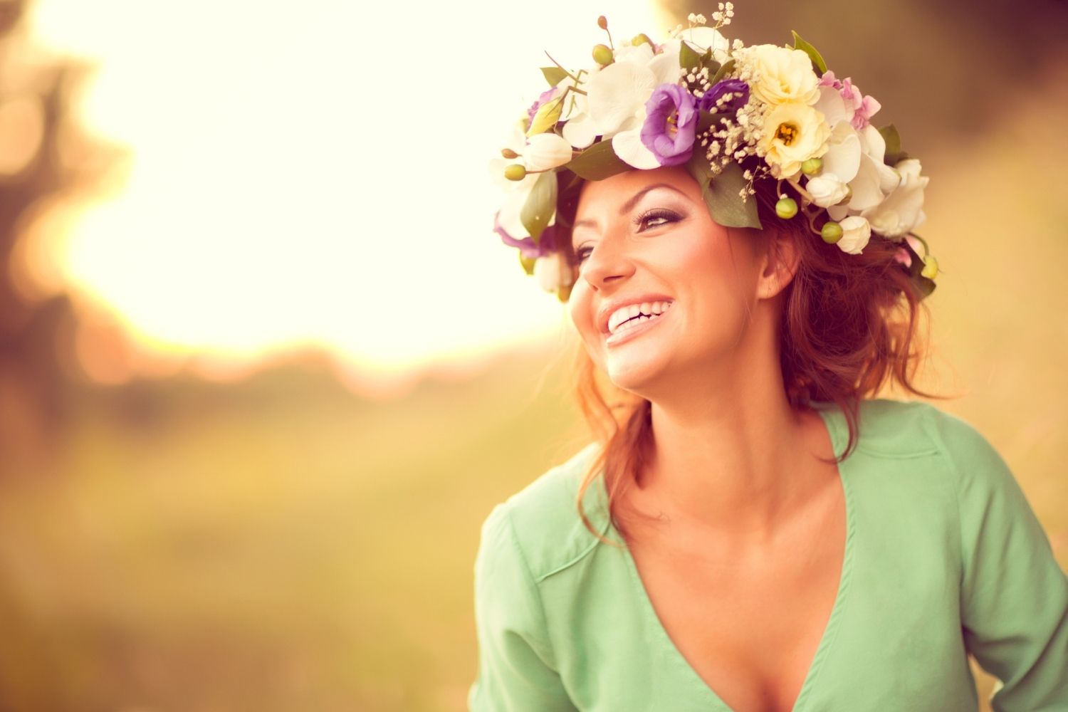 Woman smiling in soft evening light wearing a flower crown, featured in a Tess Renè Coaching article on how to live a happy life.