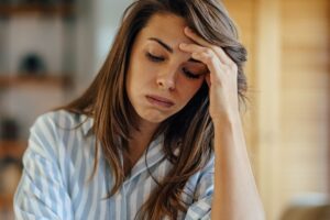 woman resting her head in her hand with eyes downcast in a Tess René Coaching article