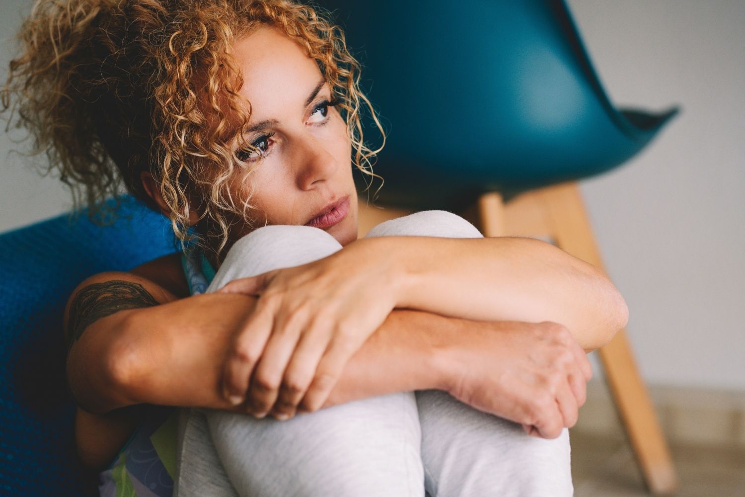 A woman sitting with her knees pulled in, reflecting on losing yourself in relationships, featured in an article by Tess Renè Coaching.
