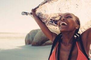 Woman laughing with open arms at the beach in this Tess René Coaching article about success and releasing the fear of shining brightly.