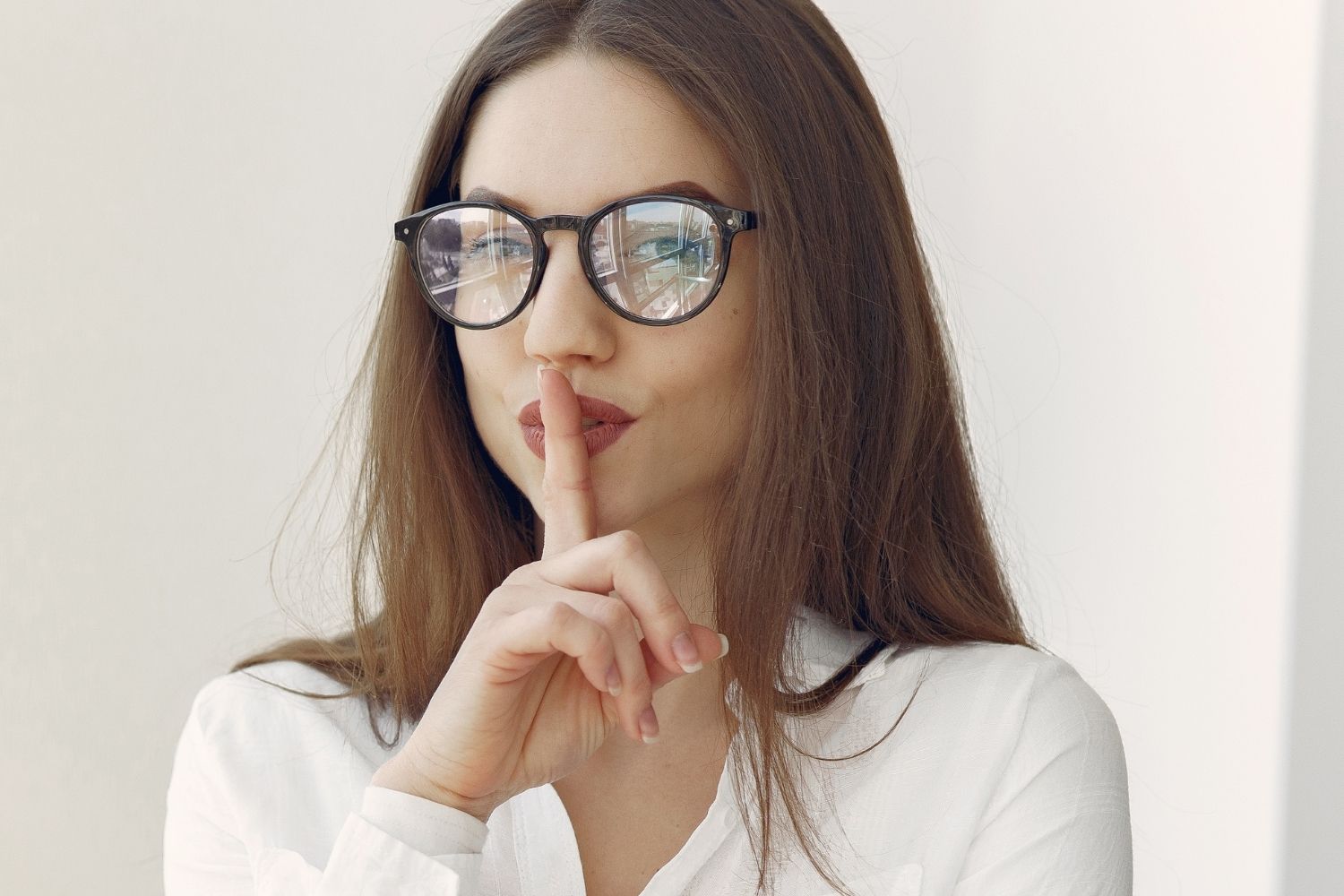 A thoughtful woman holding a finger to her lips in a quiet moment of reflection in this Tess René Coaching article on the secret of success.