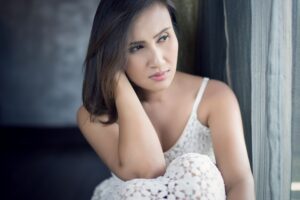 A woman staring out a window with a withdrawn expression, from an article by Tess Renè Coaching about self-abandonment patterns.