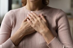 hands over heart demonstrating grounded presence and feeling emotions safely in a Tess René Coaching emotional awareness article