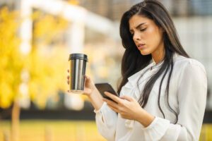 anxious professional checking phone constantly due to weak work boundaries, shown in this Tess Renè Coaching article