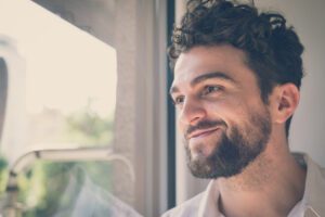 In a Tess René Coaching article, a man smiling by a window represents hope after healing inner fears about relationships.