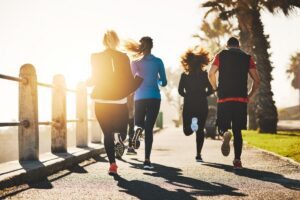 Group of runners moving forward in sunrise light, featured in this Tess René Coaching article on helping others