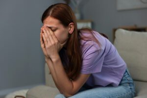 woman sitting forward with hands covering her face, appearing mentally exhausted, shown in this Tess René Coaching article