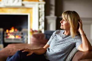 woman reclining comfortably near a fireplace, appearing at ease and self settled, in this Tess René Coaching article