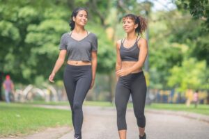 two women walking side by side outdoors in conversation, appearing relaxed and connected, shown in this Tess René Coaching article
