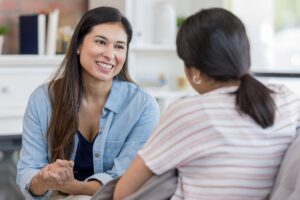 woman leaning forward over-attentively in conversation in this Tess René Coaching article about people pleasing as a learned safety strategy