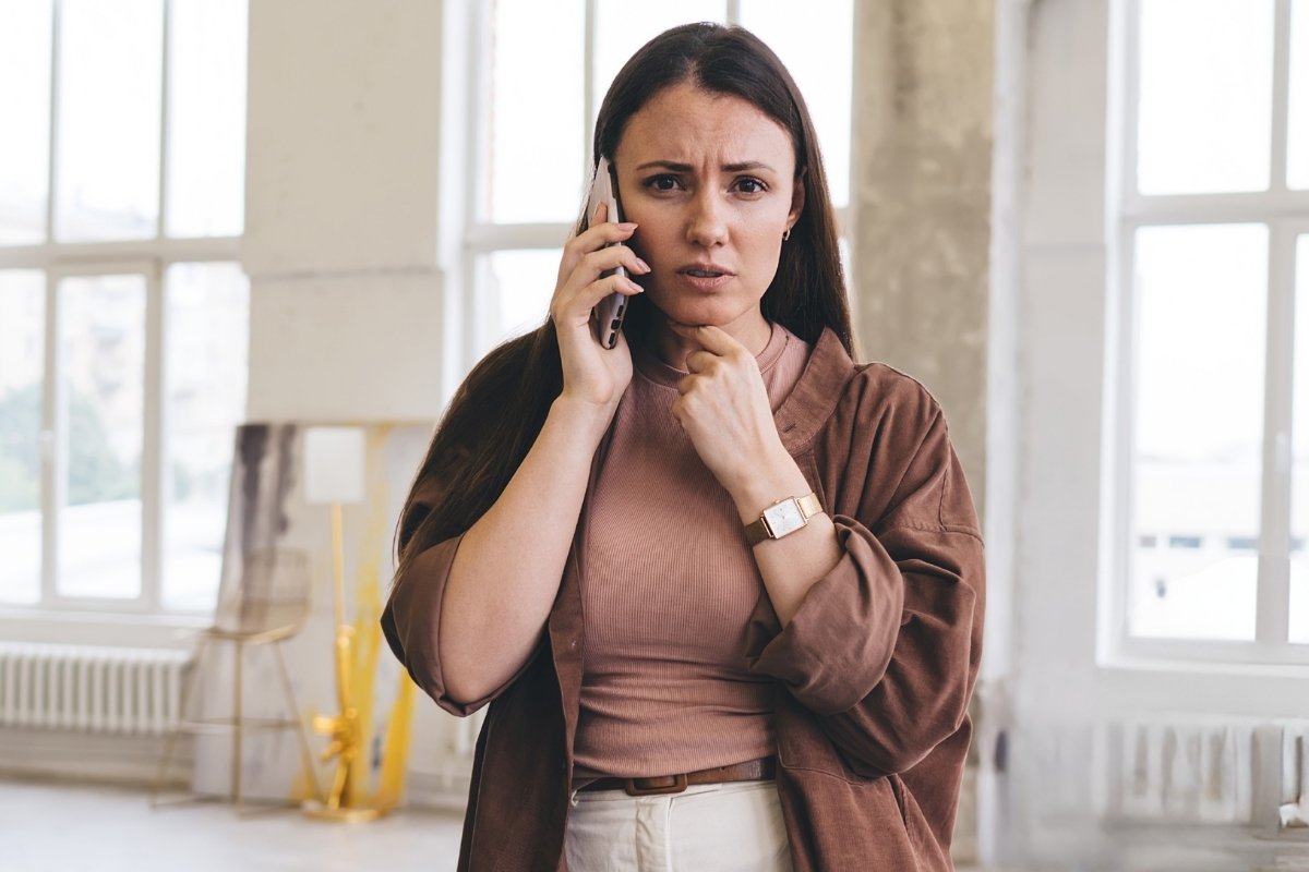 anxious woman on the phone struggling to decline a request in this Tess René Coaching article on why saying no feels safer than people pleasing