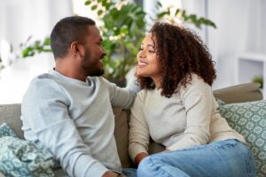 In a Tess René Coaching article, a smiling couple on a sofa shows secure connection after overthinking relationships eases