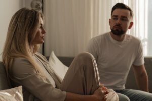 a woman sitting turned away while partner looks on in a Tess René Coaching article about the signs that overthinking is effecting your relationship.