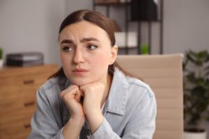 In a Tess René Coaching article, a woman resting her chin on her hands with an uncertain expression.