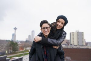 Two friends smiling and hugging outdoors, shown in this Tess René Coaching article about helping others too much