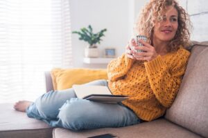 woman relaxing at home with coffee and laptop showing work life balance after setting limits, featured in this Tess Renè Coaching article