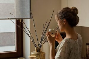 woman looking out window thoughtfully representing patience in this Tess René Coaching article on rediscovering how to find joy everyday.
