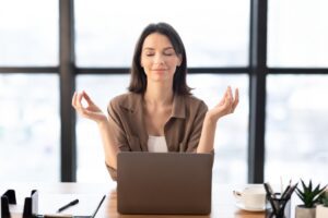 woman pausing in mindfulness at desk releasing performance pressure – Tess René Coaching
