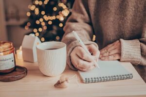 person journaling at a desk representing professional emotional support in the Tess René Coaching article on the healing and treatment of depression and anxiety