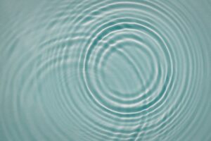 circular ripples spreading across pale blue water, illustrating regulation and emotional settling in this Tess Renè Coaching article