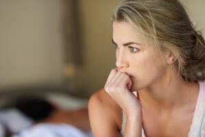 close up of a woman with her hand near her mouth and a tense expression in this Tess René Coaching article about shame and forgiving yourself