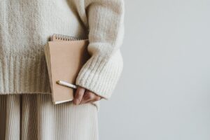 Woman holding a notebook and folder in this Tess René Coaching article about childhood patterns in relationships, attachment patterns, and how early experiences shape adult relationships