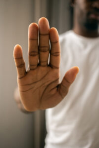 Person raising an open hand in a stop gesture in this Tess René Coaching article about emotional triggers and relationship anxiety rooted in childhood wounds