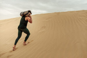 person carrying a heavy load across sand in a Tess René Coaching article about healthy guilt and emotional responsibility