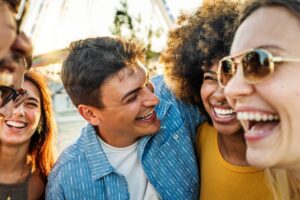 Group of friends laughing together outdoors in this Tess René Coaching article about healthy boundaries and emotional connection and secure attachment.