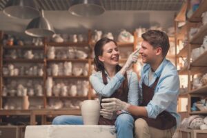 Couple smiling while shaping pottery together in this Tess René Coaching article about reparenting love and changing unconscious relationship patterns