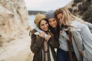three women smiling together outdoors exemplifying deeper empathy in Tess René Coaching article exploring the question: why am I so Sensitive