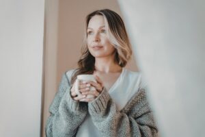 Woman holding a warm drink in this Tess Renè Coaching article about shame patterns and emotional self protection