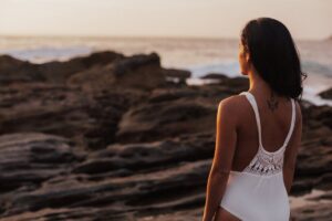 Woman standing by the ocean at sunset in a Tess René Coaching article section about celebrating yourself, recognising progress, and building self confidence